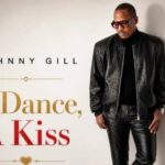 Album cover: Johnny Gill's 'A Dance, A Kiss' with Gill in a black leather outfit against a light background.