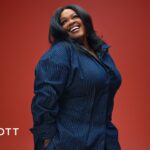 Jill Scott smiles in a blue pinstripe shirt against a red backdrop, COLORS Studios logo in the upper left.